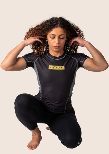 Women’s technical BJJ rashguard in black and gold, featuring four‑way stretch and mesh ventilation.