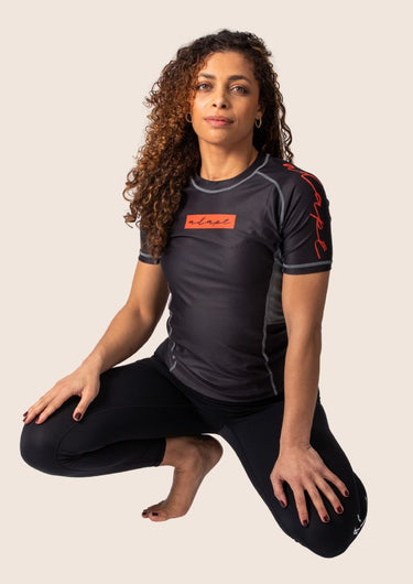Women’s technical BJJ rashguard in black and red, featuring four‑way stretch and mesh ventilation.