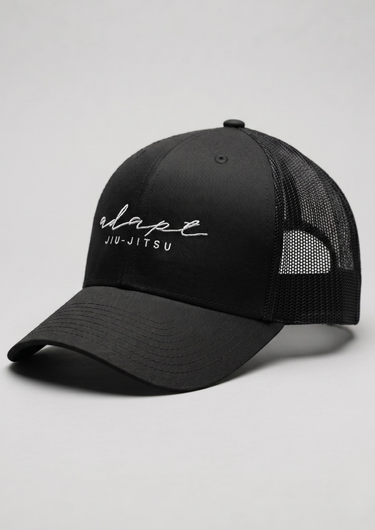 A black trucker-style baseball cap with a curved brim, black mesh back panels, and white embroidered text reading 'elapse JIU-JITSU' on the front, photographed on a light gray studio background.