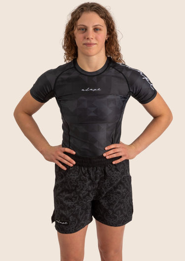 Unisex Jiu-Jitsu dual‑layer combination shorts with black paisley pattern; built‑in compression liner; adjustable fit. Womens Prism BJJ rashguard in black Jacquard Lycra with geometric prism pattern, short sleeves, compression fit.