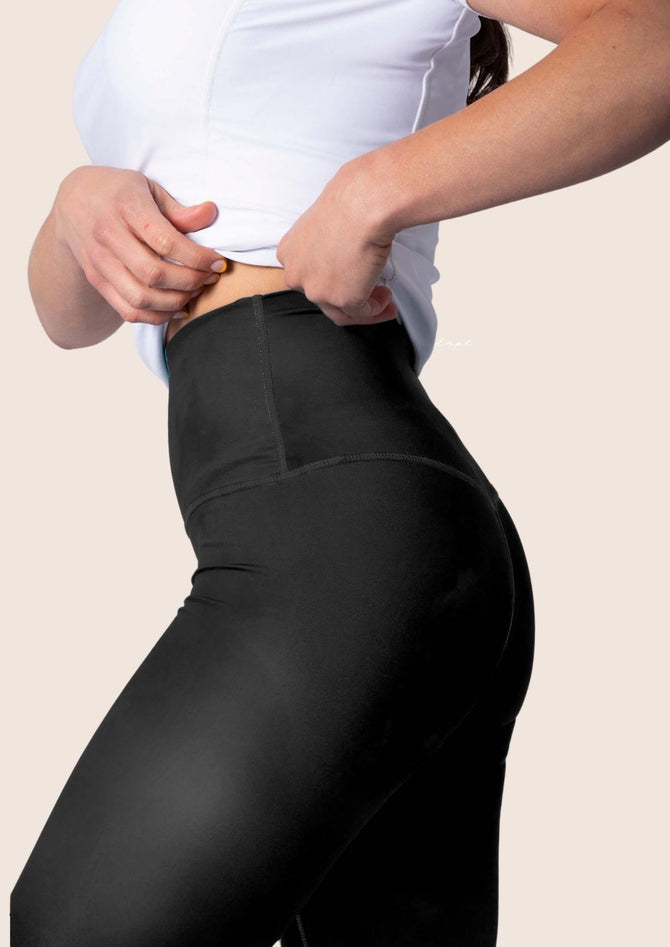 Women’s black training leggings with script logo, high‑waisted; flexible fabric.