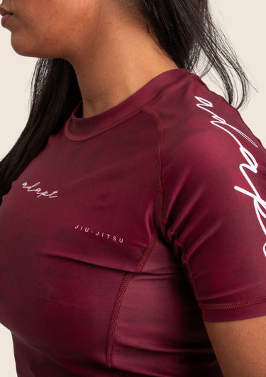 Women’s prism BJJ rashguard in maroon with geometric prism design; short sleeves.
