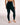 A model from behind wearing high-waisted black leggings, standing barefoot against a plain white studio background.