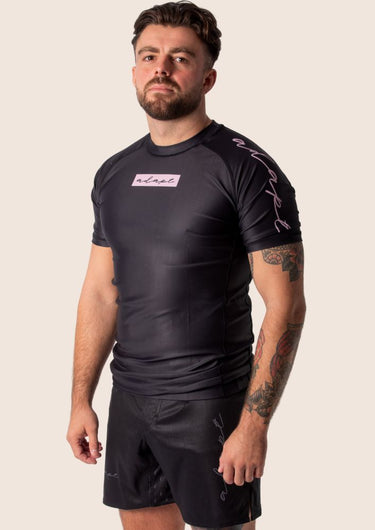 Men’s original BJJ rashguard with pink geometric design on black background.