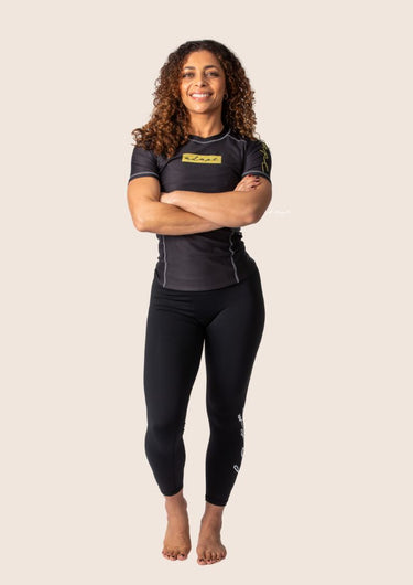 Women’s technical BJJ rashguard in black and gold, featuring four‑way stretch and mesh ventilation.