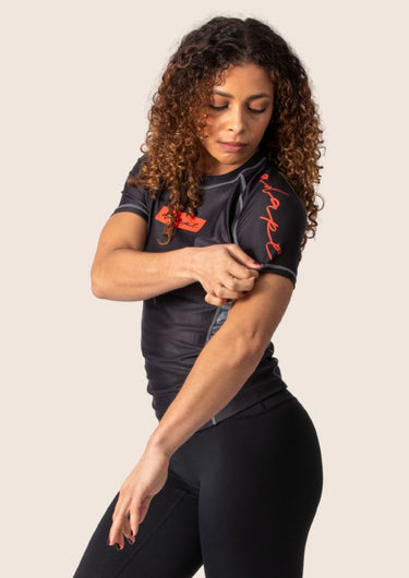 Women’s technical BJJ rashguard in black and red, featuring four‑way stretch and mesh ventilation.