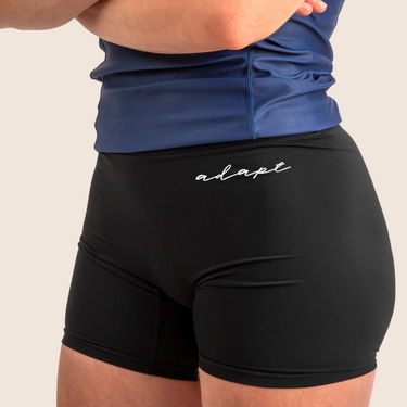 Women’s mid‑length compression shorts in black; high‑waisted design; moisture‑wicking fabric.