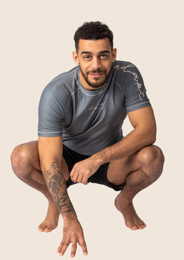 Men’s ash‑rose technical BJJ rashguard with muted pink‑rose hue and performance mesh panels