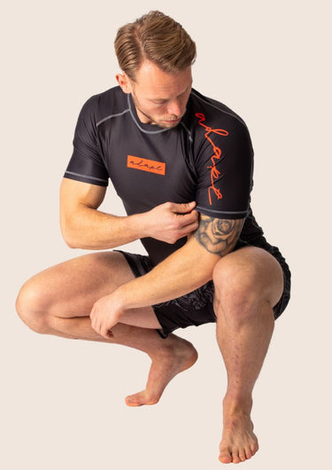 Men’s technical BJJ rashguard in black and red, featuring four‑way stretch and mesh ventilation.