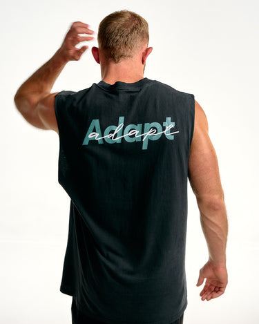 A man viewed from behind wearing a sleeveless black athletic tank top with the word 'adapt' printed across the back in teal and white script, against a plain white studio background.