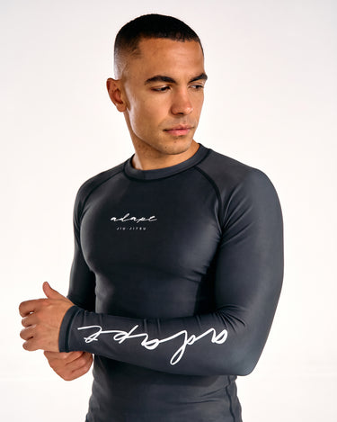 A man modelling a black long-sleeve rashguard and matching black shorts.