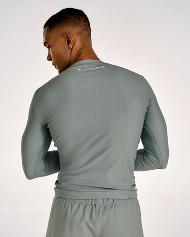 A man shown from the back wearing a fitted long-sleeve athletic top and matching shorts in a muted olive green color, against a plain light background.
