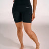 Black high-waisted BJJ compression shorts with a small white script logo on the left hip, shown on a model from the back against a plain white studio background.