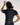 A woman shown from behind wearing a fitted black BJJ short-sleeve rashguard with white script branding on the back and shoulders, posed against a plain light background.