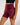 A close-up of a model wearing high-waisted BJJ compression shorts in maroon with a small white script logo on the front, paired with a black sports bra against a plain light background.