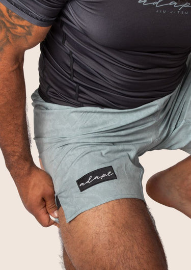 Unisex dual‑layer combination shorts with sage green paisley pattern; built‑in Lycra liner; secure fit.