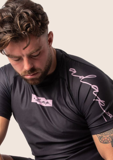 Men’s original BJJ rashguard with pink geometric design on black background.