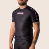 Men’s original BJJ rashguard with pink geometric design on black background.